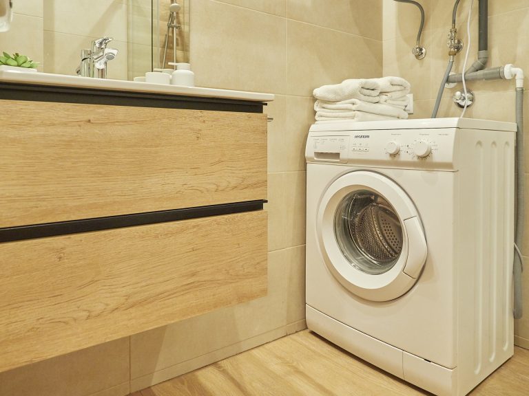 Bany amb rentadora i moble de fusta a l'apartament MENTA de Grün Estudis, Pas de la Casa