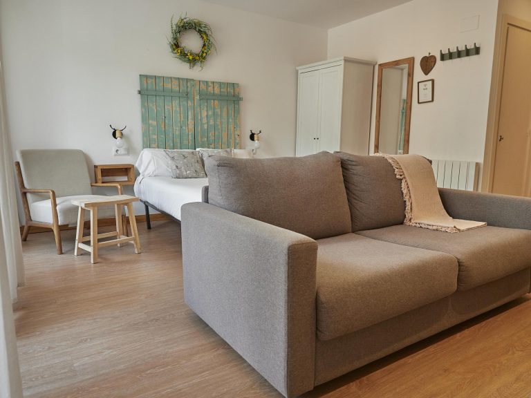 Sofà llit doble davant del llit amb capçal verd a l'apartament MENTA de Grün Estudis, Pas de la Casa