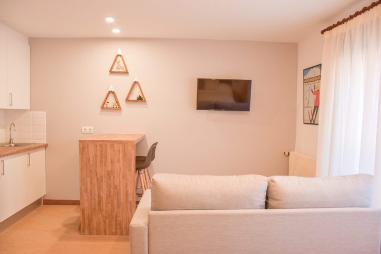 Sala d'estar amb sofà, barra de fusta i televisor a l'apartament ROC de Grün Estudis, Pas de la Casa