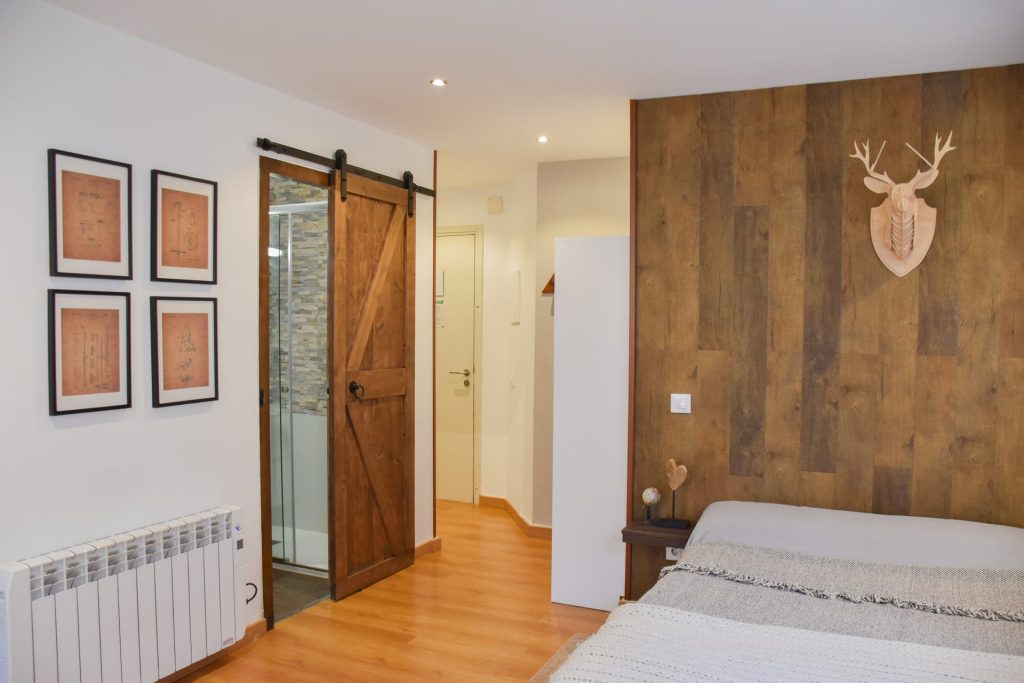 Apartament SKY al Pas de la Casa: dormitori amb paret de fusta, cap de cérvol decoratiu i porta corredissa al bany