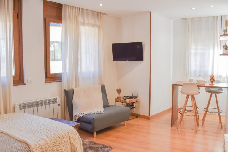 Sala d'estar amb sofà, televisor i taula alta a l'apartament SKY de Grün Estudis, Pas de la Casa