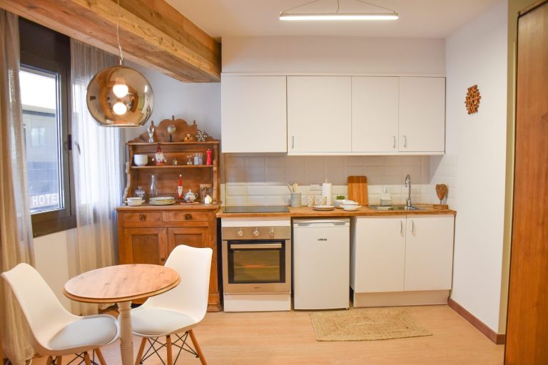 Cuina equipada amb moble de fusta i taula rodona a l'apartament WOODY de Grün Estudis, Pas de la Casa
