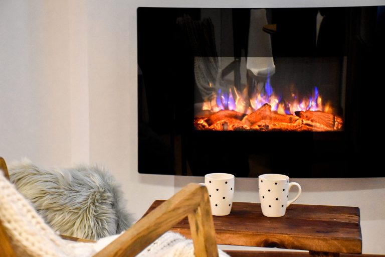 Llar de foc elèctrica encesa amb dues tasses a l'apartament WOODY de Grün Estudis, Pas de la Casa