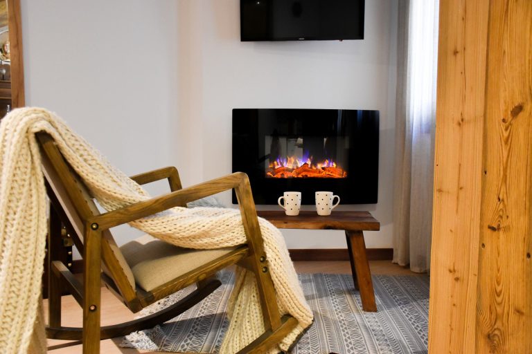 Racó de la llar de foc elèctrica amb balancí de fusta a l'apartament WOODY de Grün Estudis, Pas de la Casa
